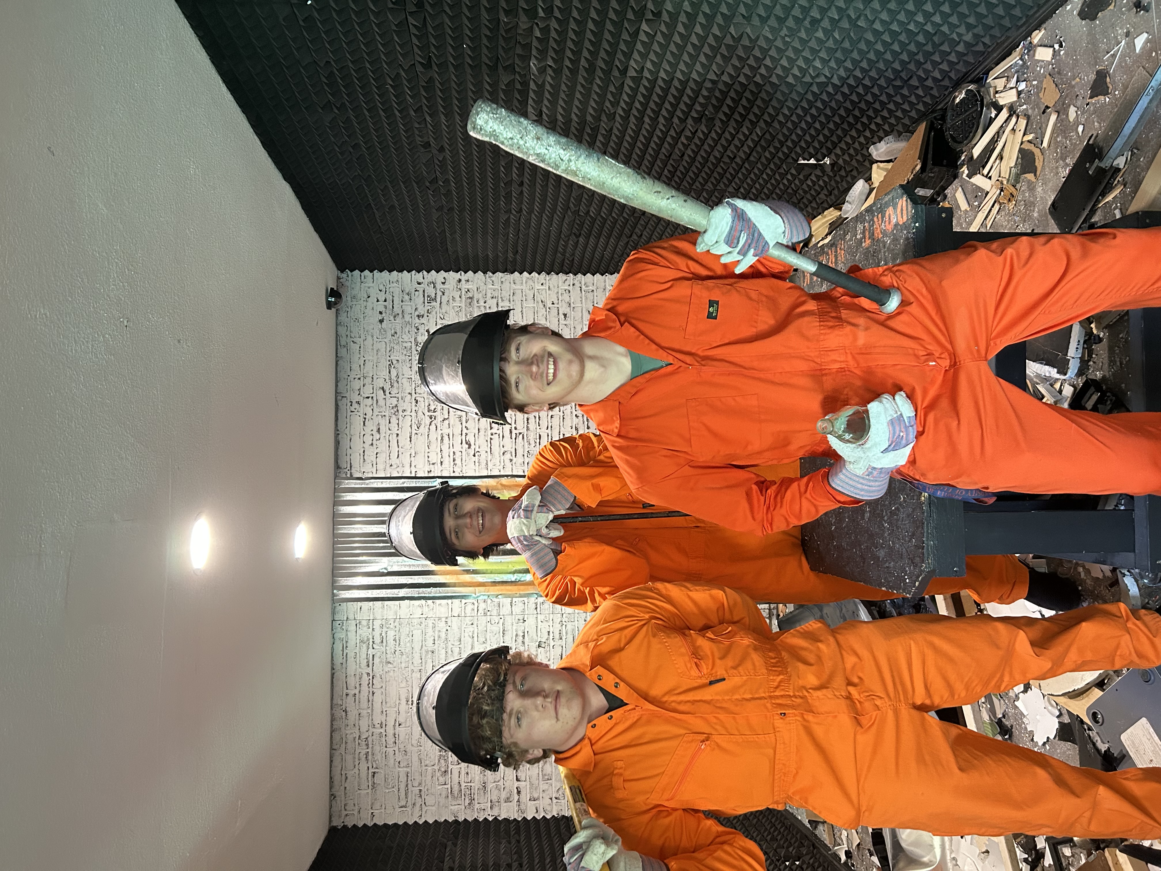 Three Crash Out customers celebrating inside the smash room surrounded by debris